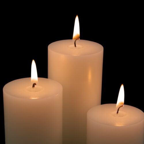 Close,Up,Of,White,Candles,Burning,On,Black,Background. Luz en la oscuridad